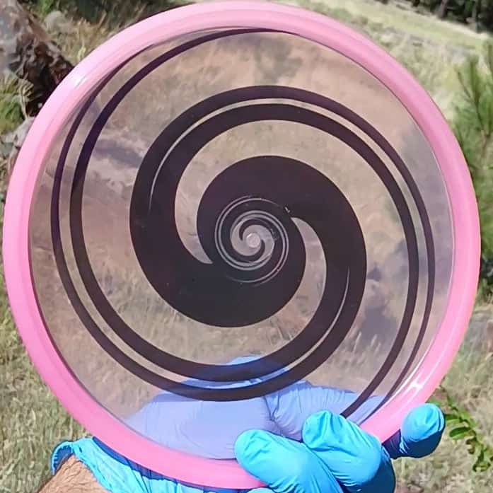 040102.03 Maestro Double Spiral disc golf midrange with custom geometric design. Pink disc with black spirals.