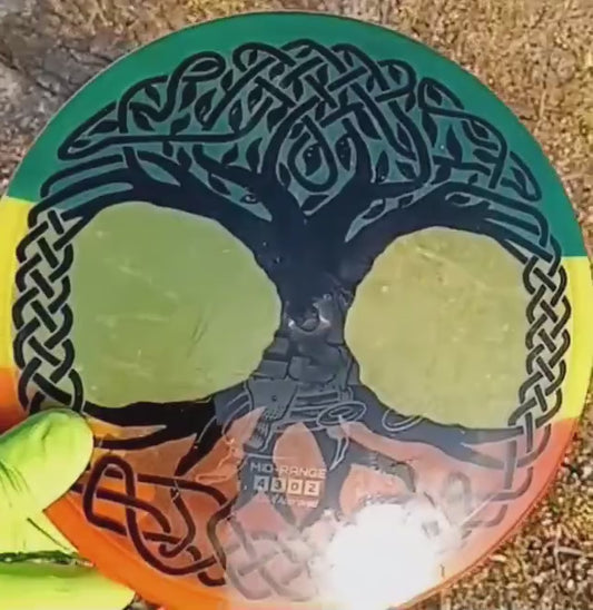 040102.22 Maestro Celtic Tree of LIfe disc golf midrange from Discmania. Yellow disc with red and green dyed patterns for a rasta effect.