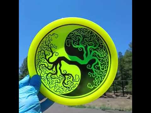 Latitude 64 opto River yellow with black stencil design and green tree in a desert scenario. Understable fairway driver with yin yang Tree of Life design